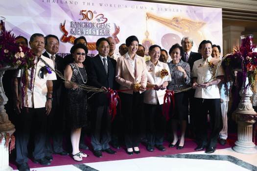 Thailand's Prime Minister Yingluck Shinawatra, centre, cuts the ribbon at the opening of the 50th Bangkok Gems & Jewelry Fair, while to her left, Somchai Phornchindarak, president of TG JTA , and other dignitaries look on.