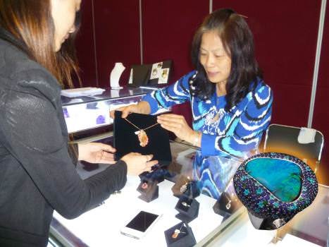 Emily Zhang, of Different Gems, shows a pendant made of Mexican fire opal jewelry. The inset shows a black opal ring with sapphire, tsavorite, and Paraiba tourmaline accents. With an office in Germany and China, the company is the exclusive importer of Mexican fire opals into China.