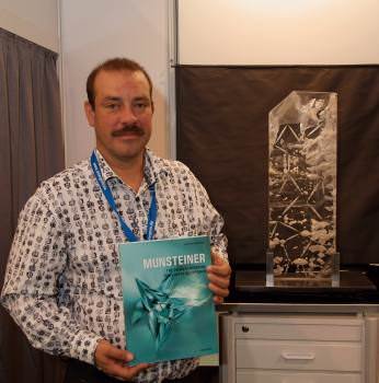 Tom Munsteiner holds a new book showcasing the work of himself and his wife Jutta. To the right is one of Munsteiner's stone sculptures (photo: Dierick Bevoort of Diebe Media).