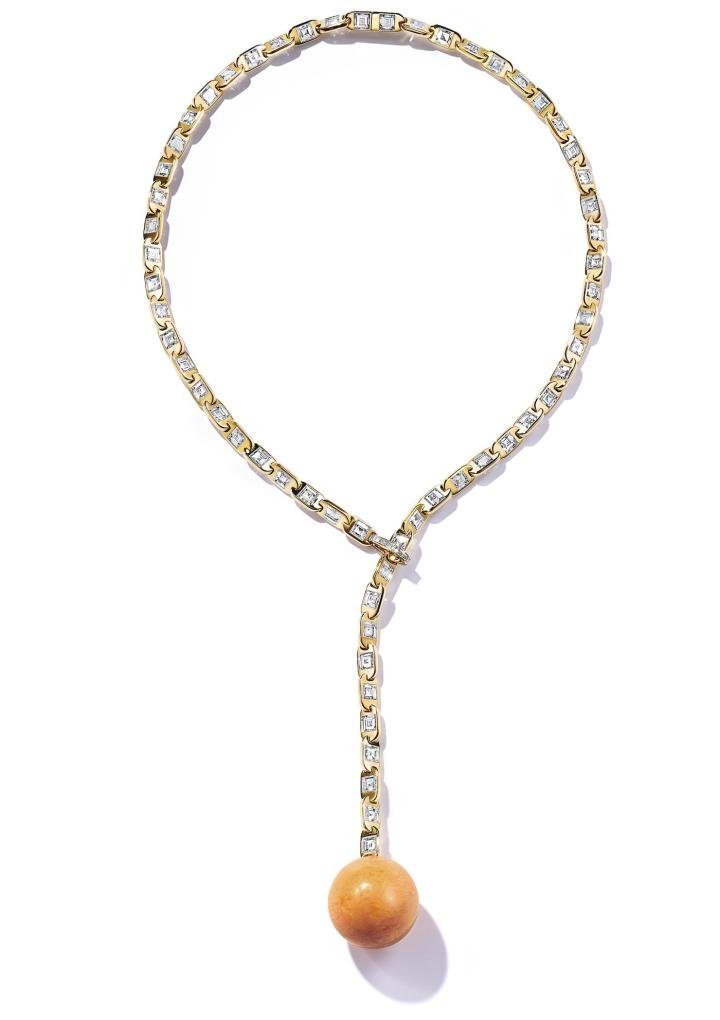 A rare Melo Melo pearl of over 95 carats glows bright orange as it suspends from a 18k yellow gold and diamond chain.